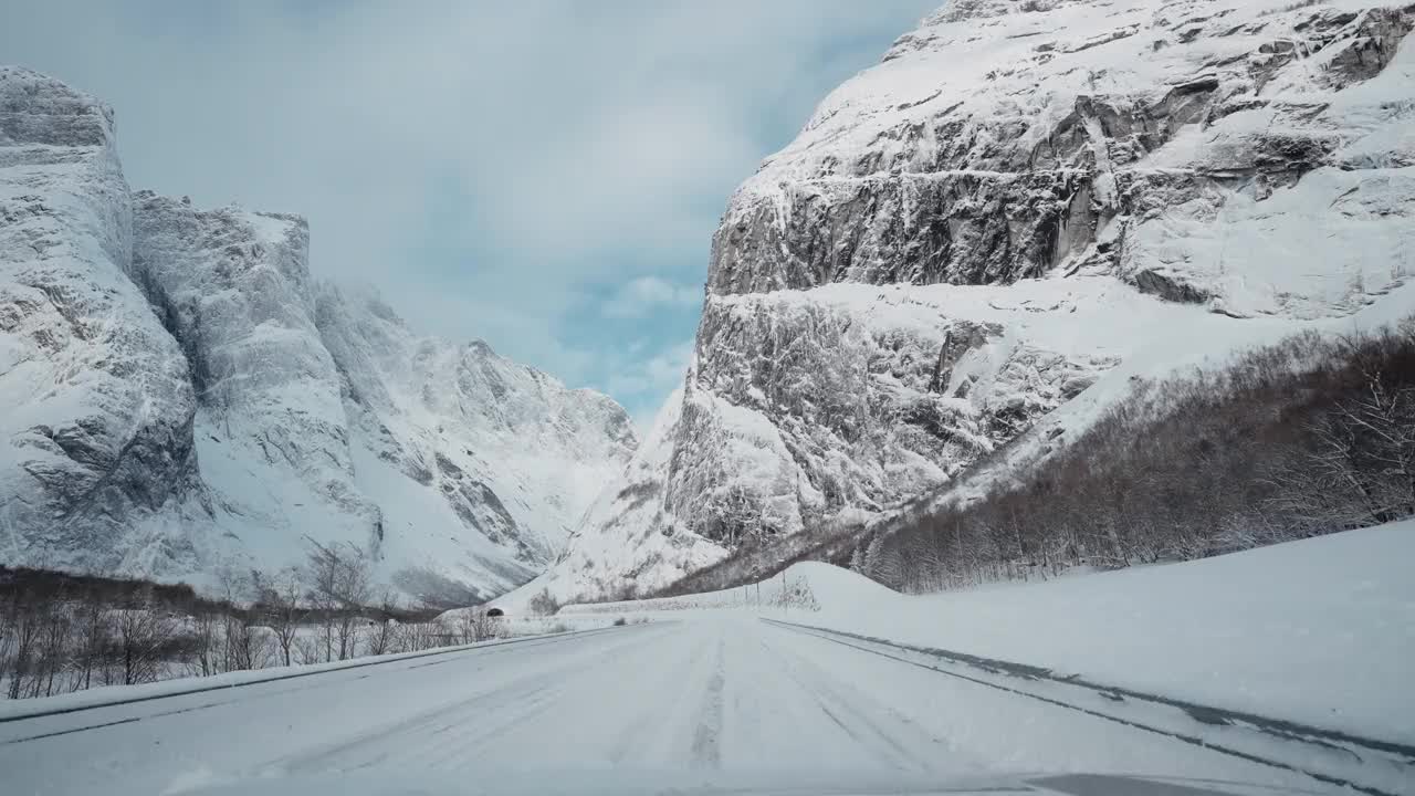 令人惊叹的POV驾驶穿越挪威雄伟的白雪覆盖的景观，经过Trollveggen，迷人而令人振奋的山腰奇观视频素材