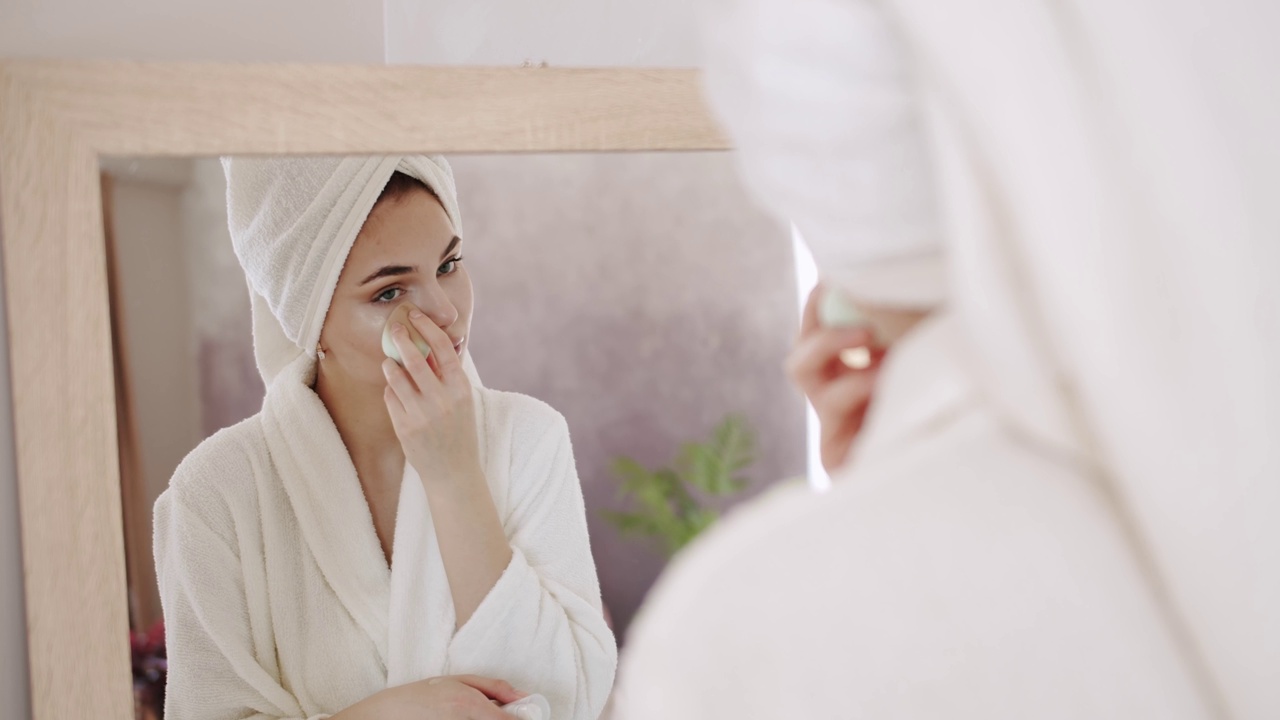 女士在脸上涂抹护肤霜，使脸部柔软清新视频素材