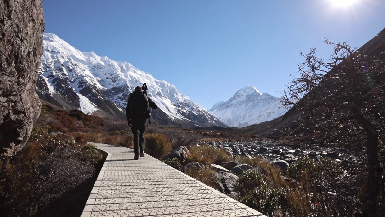 一个年轻人背着背包和摄影器材踏上了登山之旅视频素材