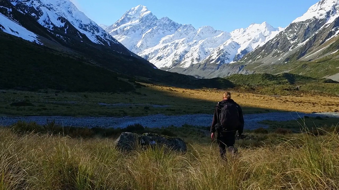 一个年轻人背着背包和摄影器材踏上了登山之旅视频素材