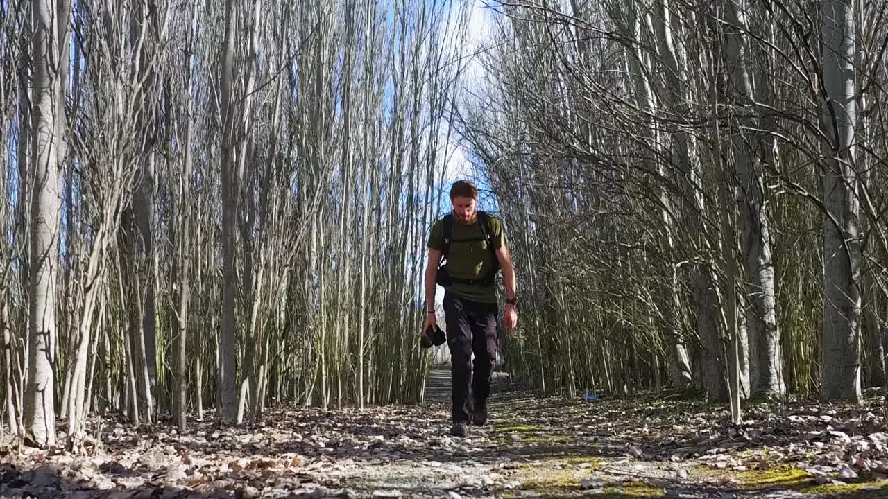 一个年轻人背着背包和摄影器材踏上了登山之旅视频素材