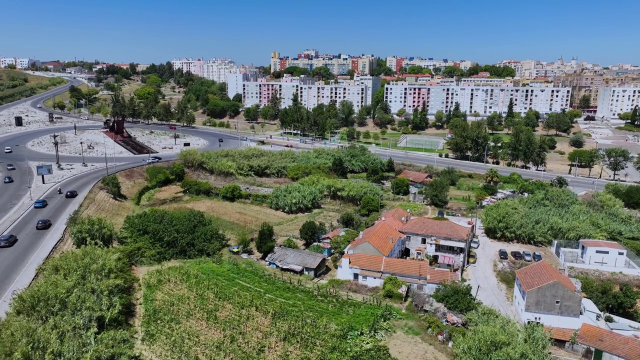 无人机拍摄的一条道路上有一个环形交叉路口，里面有一个大纪念碑。还飞过了路边的一个小农场。视频素材