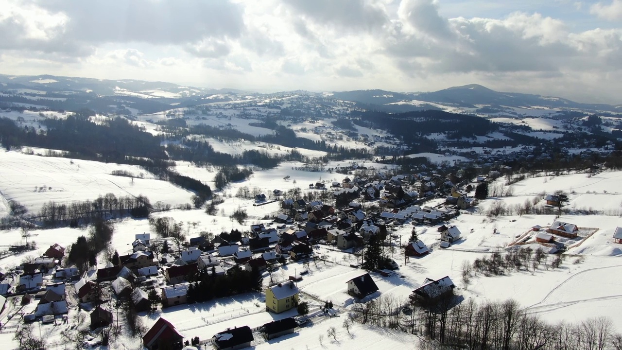 冬日阳光明媚的一天，白雪覆盖的山村里的典型房屋。空中的回调视频素材