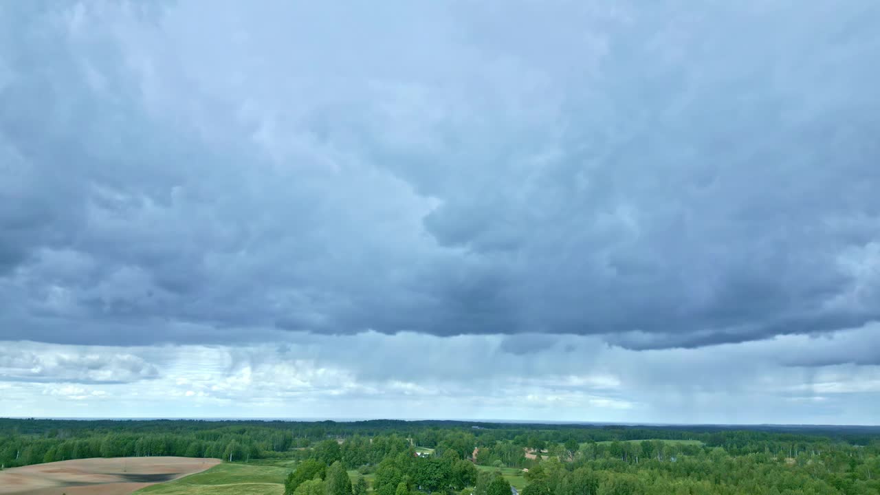 空中无人机观察拉脱维亚乡村森林景观上的灰色云层，远处有小雨。视频素材