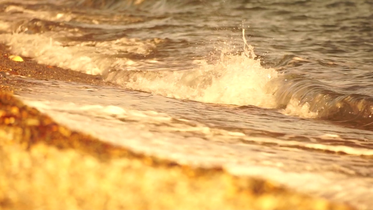 小海浪，模糊的软泡沫海浪冲刷金色卵石沙滩夕阳。海滩上的海浪。没有人。假日休闲概念。抽象航海夏季海洋日落自然背景。视频素材