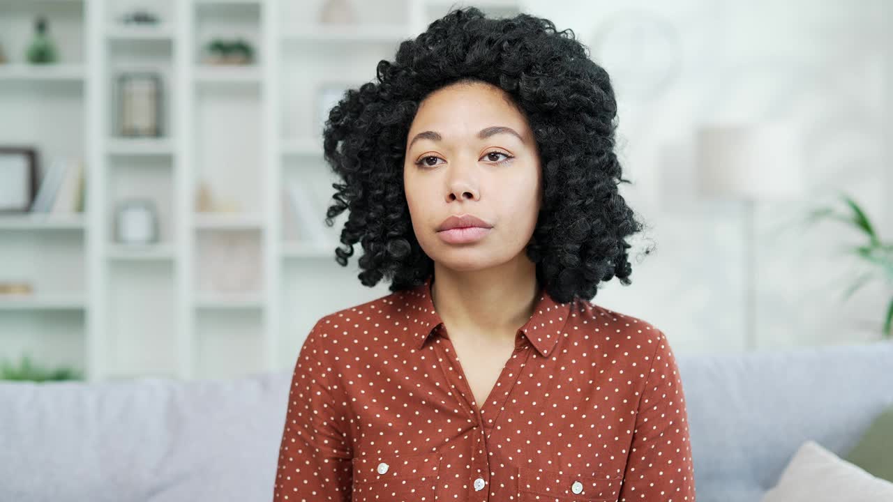 疲倦的非裔美国女性坐在家里的沙发上遭受眼睛疲劳视频素材