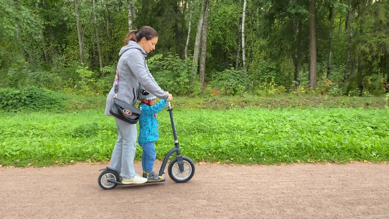 妈妈和蹒跚学步的小男孩在公园里骑摩托车视频素材