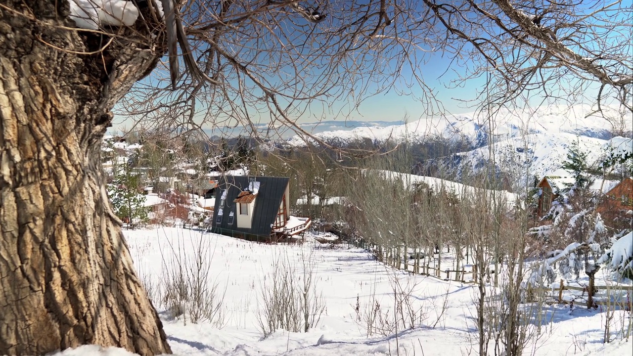 在智利的圣地亚哥，从积雪的林地山坡上俯瞰安第斯山脉山谷中风景秀丽的Farellones村庄视频素材