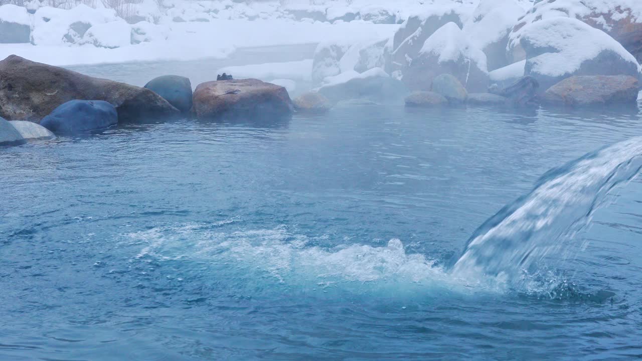 固定的自然场景，水流入热气腾腾的天然温泉被雪包围在科罗拉多州的山区视频素材