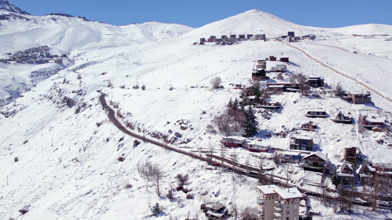 在一个阳光明媚的日子里，在智利，与El Colorado和La Parva滑雪胜地一起建立积雪的Farellones的空中轨道视频素材