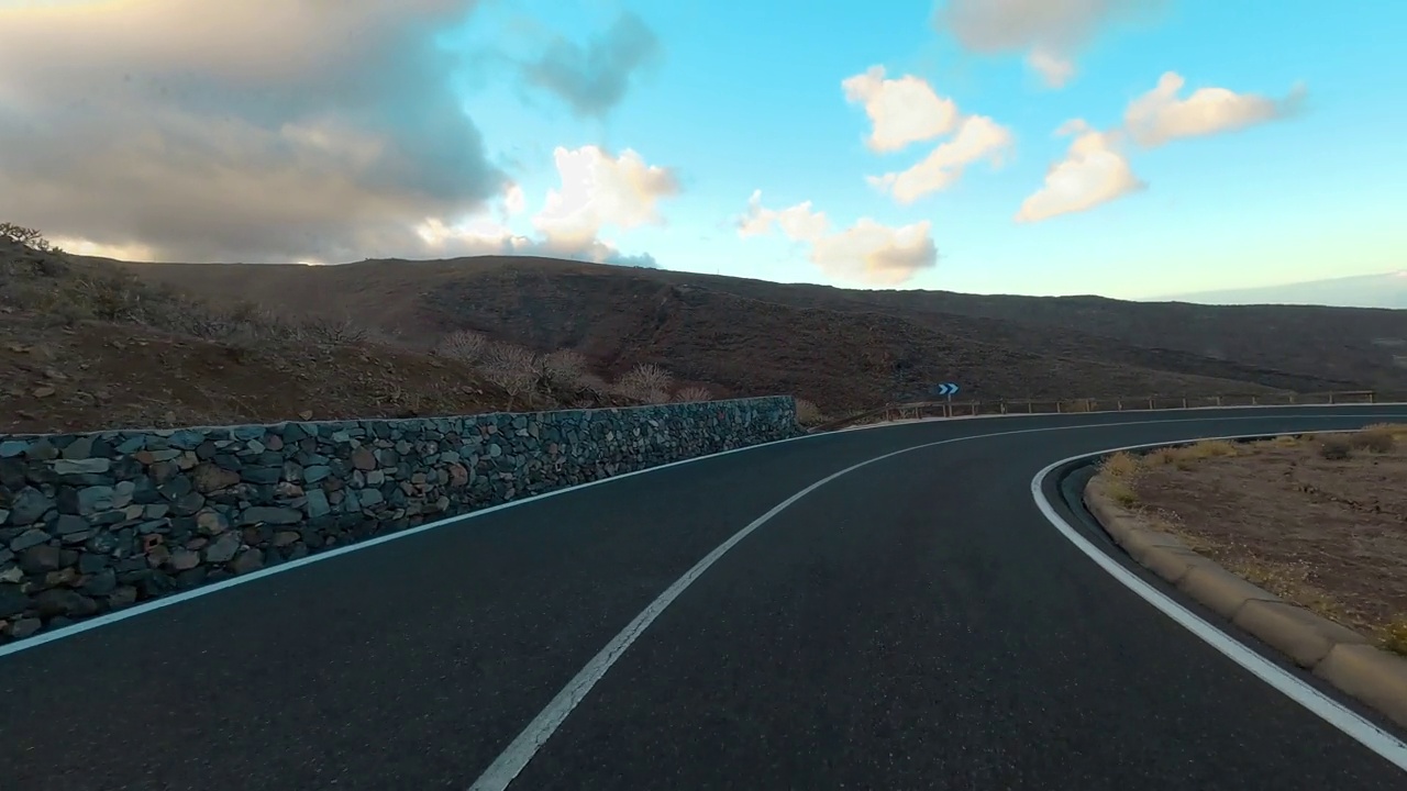 在蓝天和地平线的背景下，在一条长长的柏油直路上开车。旅游和交通的概念。山区国家公园。开车到目的地。节日假期。视频素材