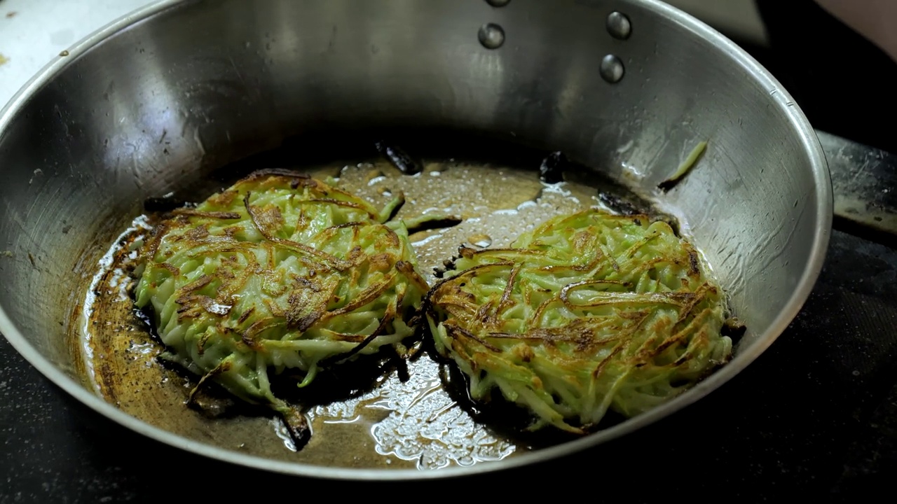 土豆和西葫芦煎饼都是在平底锅里煎的，土豆煎饼在油里煎，平底锅煎近景，吃素视频素材