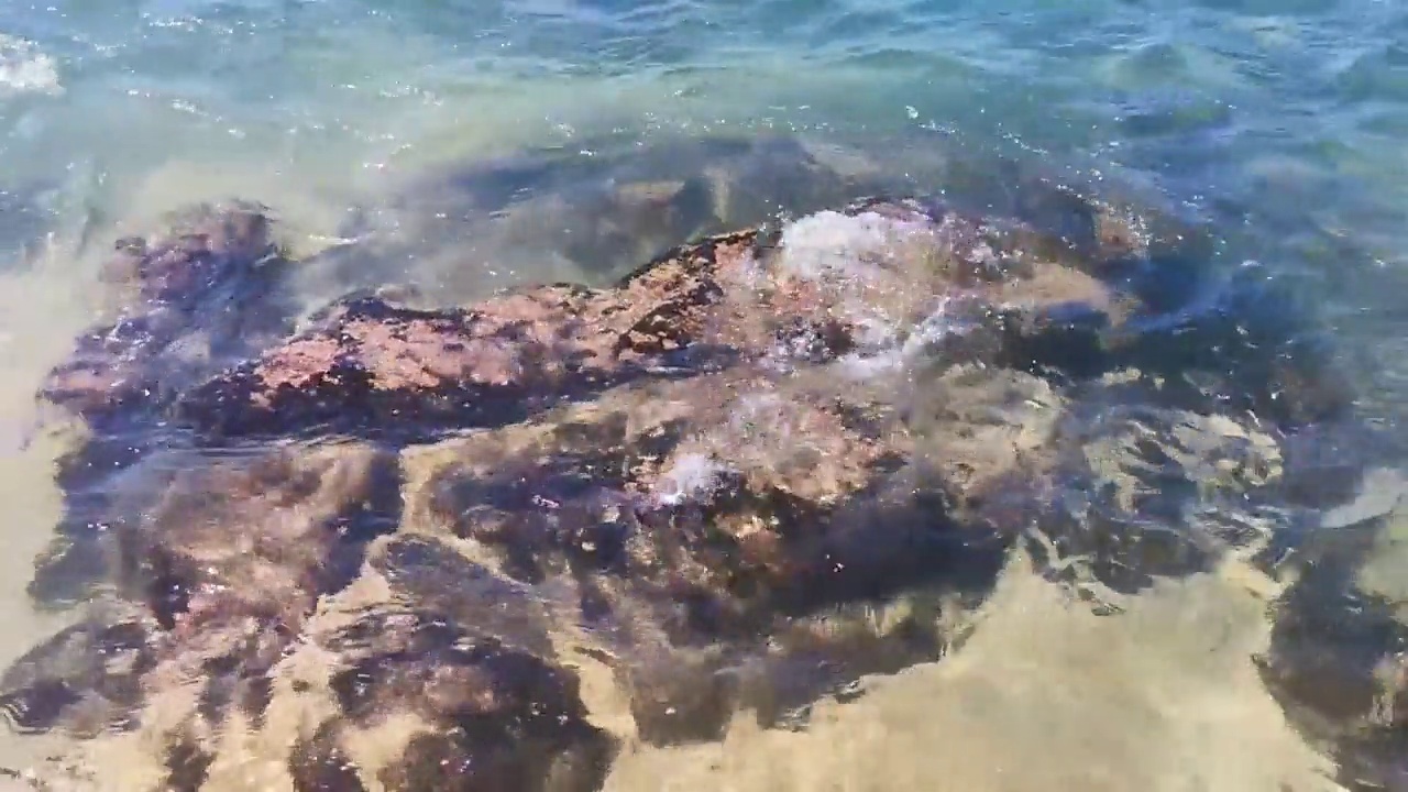 海滩沙滩蓝色绿松石水波浪岩石全景埃斯孔迪多港。视频素材