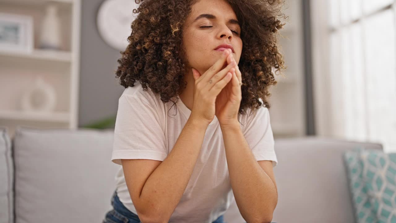 年轻漂亮的西班牙女人坐在家里的沙发上，脸上带着严重的焦虑视频素材