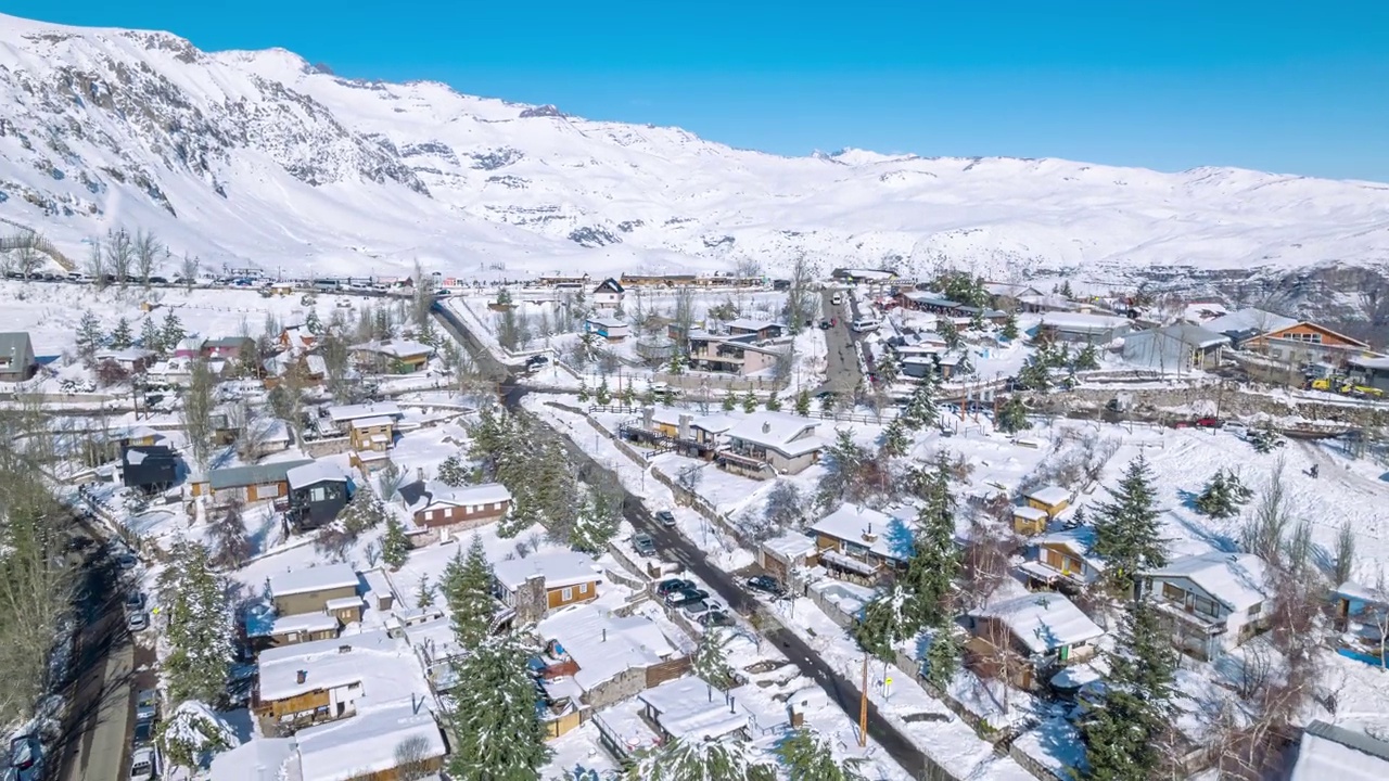 在轨道上的视差效果的空中超缩在完全积雪的村庄法雷洛内斯，雪山在背景中，智利视频素材