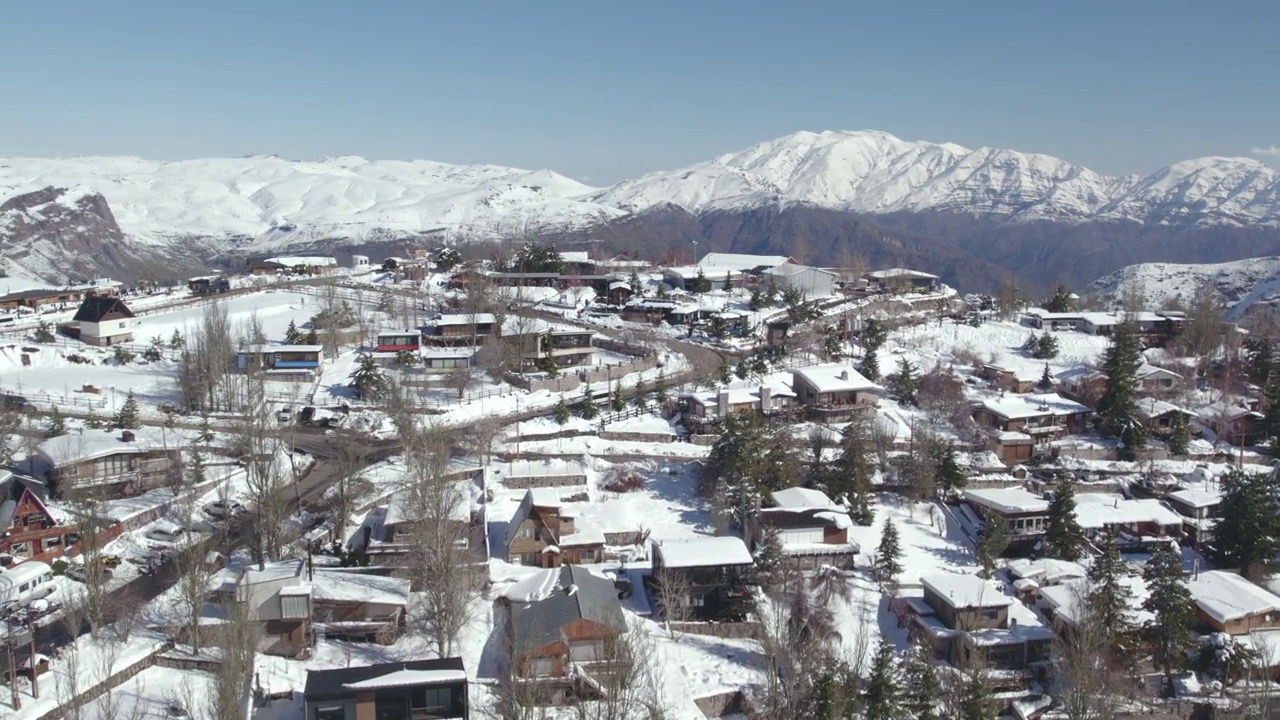 鸟瞰图的滑雪胜地小镇与雪山在背景，视差运动拍摄视频素材