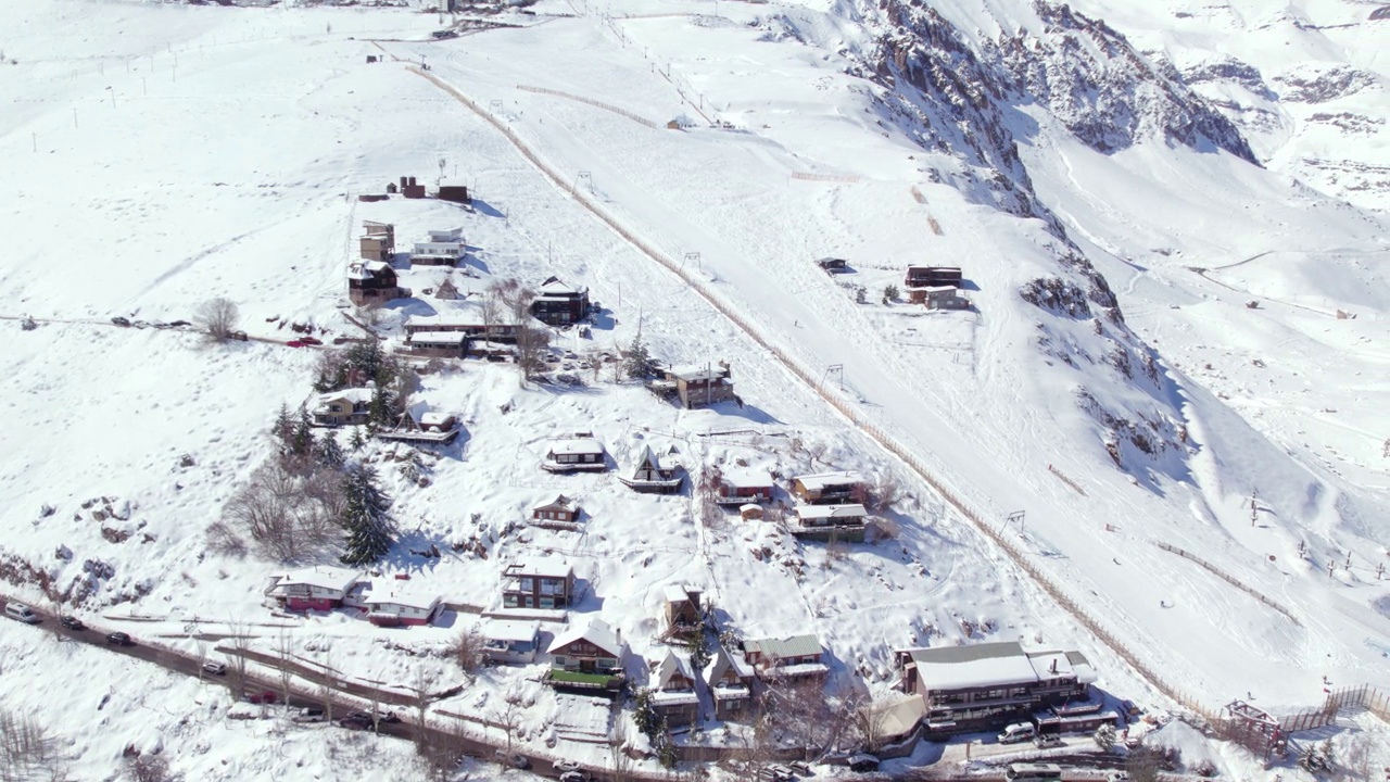 空中轨道建立欧洲风格的山间小屋在雪村法雷洛内斯和滑雪者下降法雷洛内斯公园智利视频素材