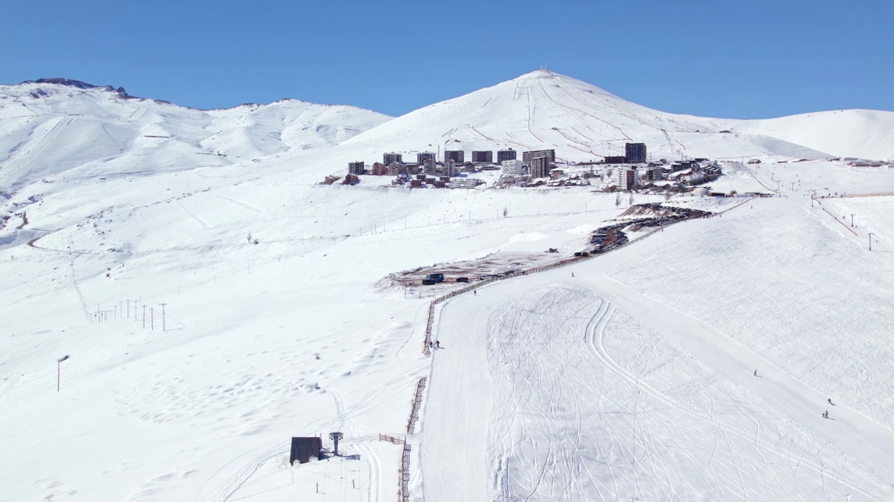 鸟瞰在智利圣地亚哥陡峭的雪覆盖的山谷斜坡上的Farellones滑雪场视频素材