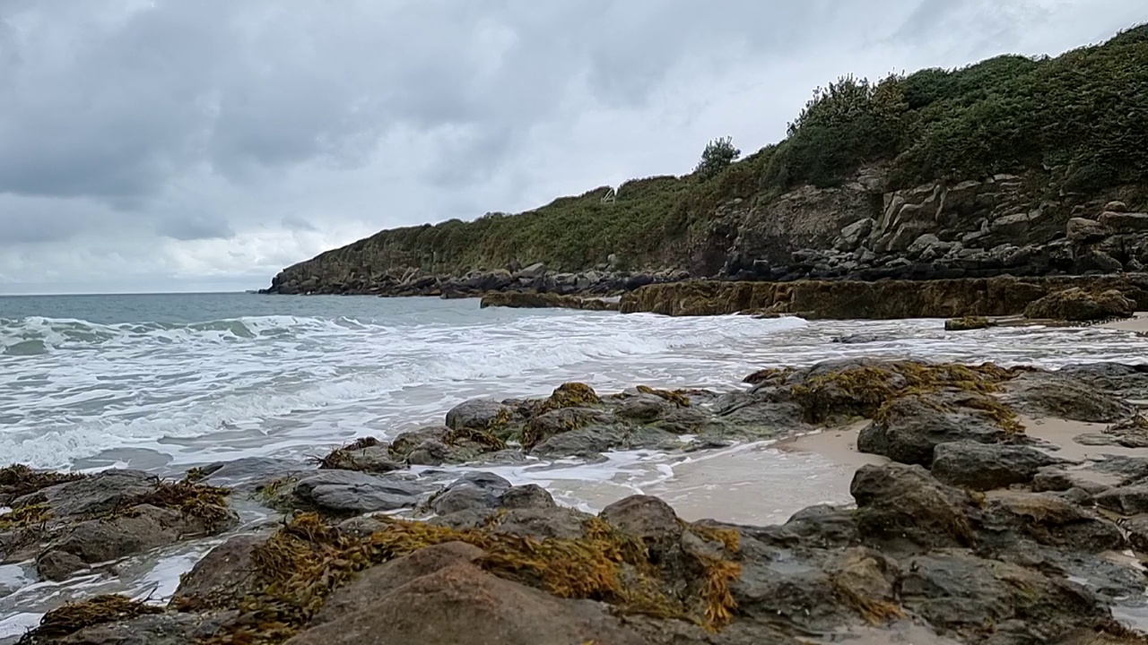 慢动作的海浪冲刷岩石海岸海岸线和崎岖的海湾悬崖横跨天际线视频素材