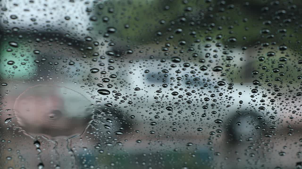 汽车挡风玻璃内的特写背景，外面有雨滴。视频素材