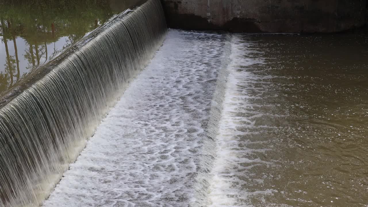 背景图:水流穿过混凝土屏障溢流坝的表面。视频素材