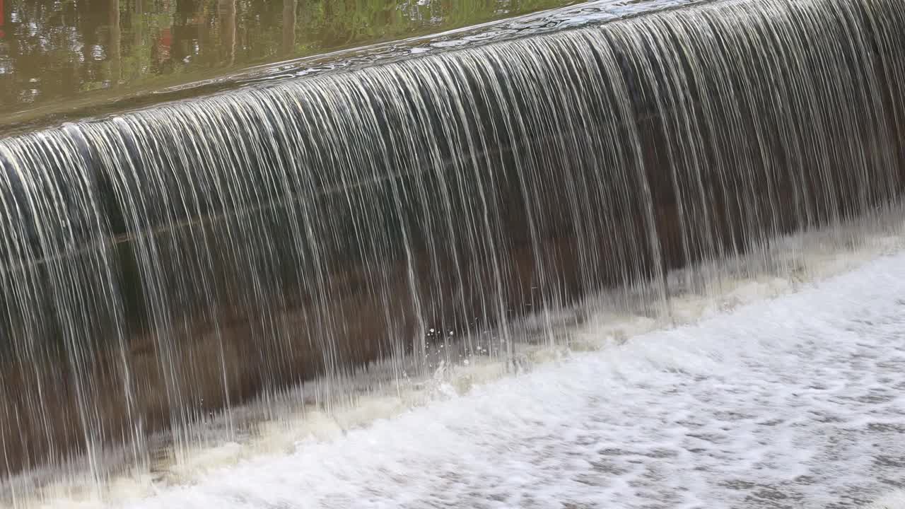 背景图:水流穿过混凝土屏障溢流坝的表面。视频素材