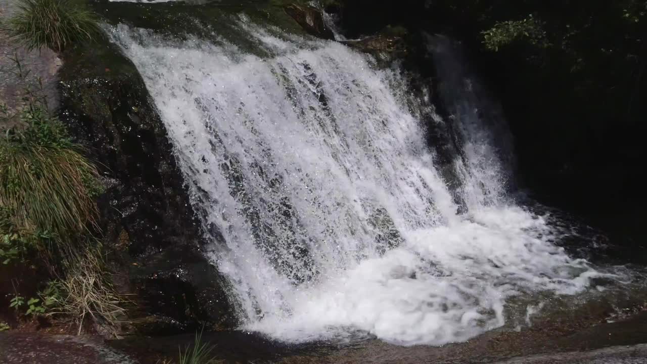 美丽的瀑布在山间河流的石头之间，慢动作视频素材