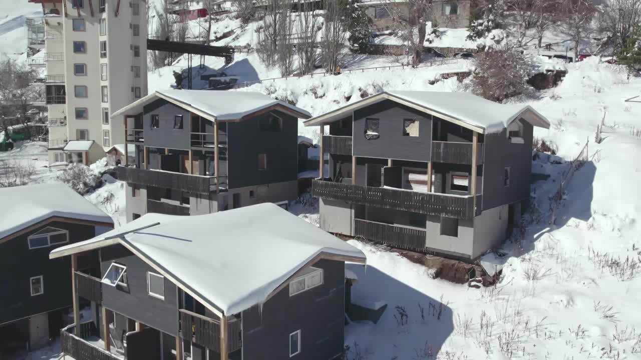 近距离鸟瞰图，在智利的Farellones白雪皑皑的山村，木材和石头建造的小屋正在建造中。视频素材