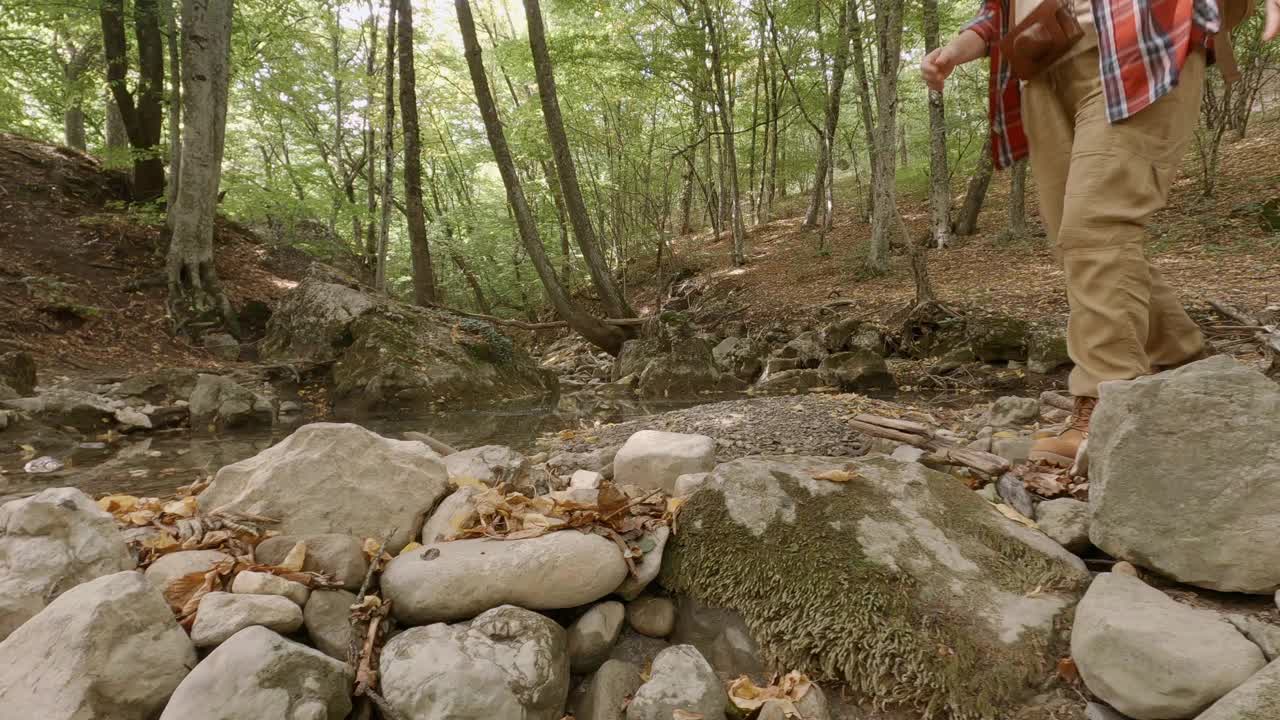 女旅行者在石头上行走，穿过森林中的山涧视频素材