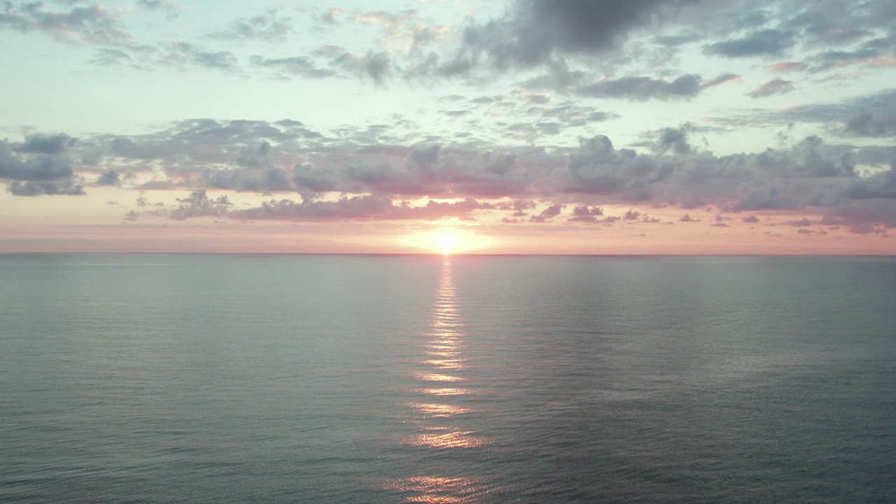 日落在平静清澈的海面上，海浪滚滚而来。戏剧性的云。空中推入镜头。图伦、墨西哥视频素材