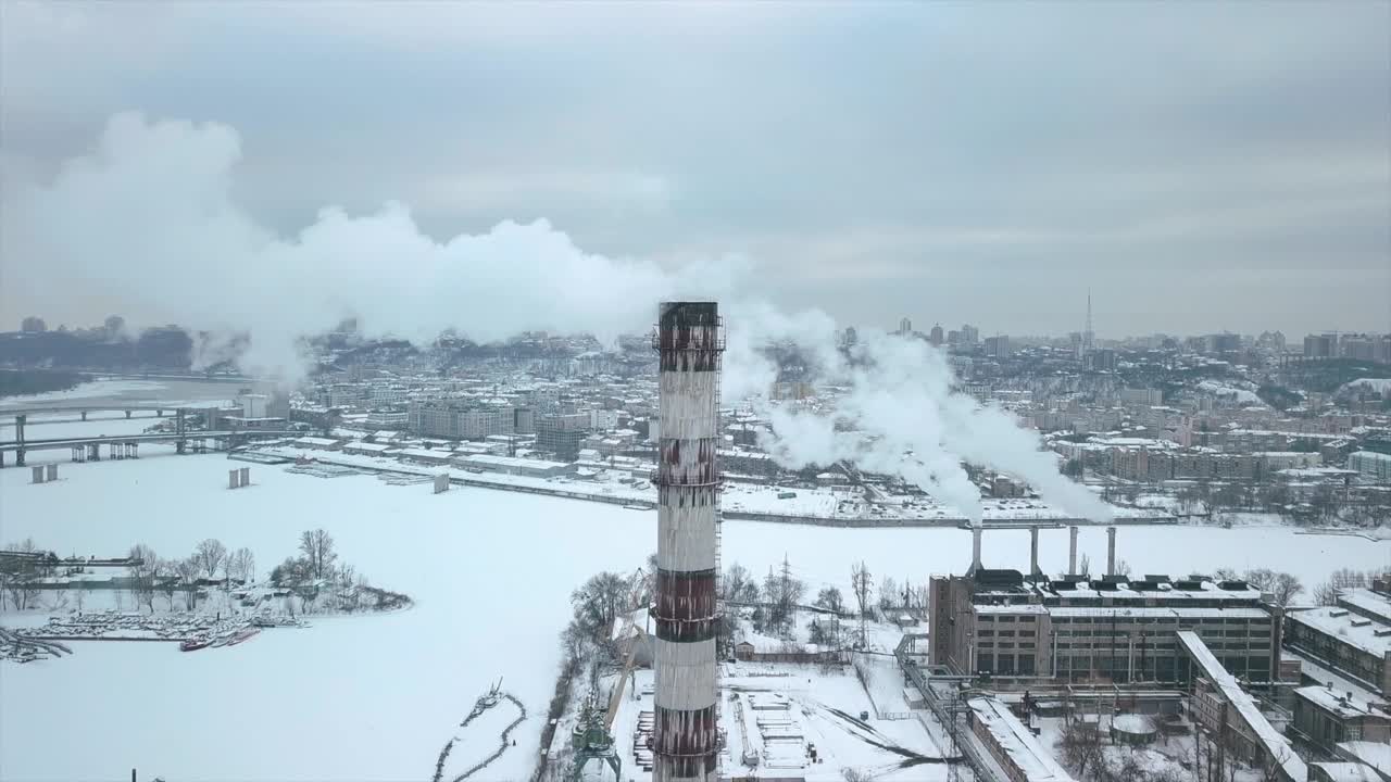 在工业区上空飞行到热电网络的管道，装载码头装有冰中的冷冻水。城市的背景映衬着缕缕烟雾。视频下载