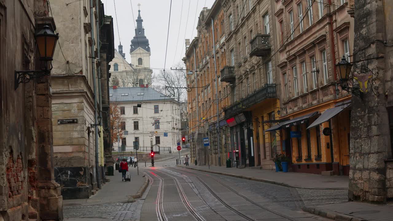一辆有轨电车驶过利沃夫空荡荡的狭窄街道。安静的阴天秋天的早晨视频下载