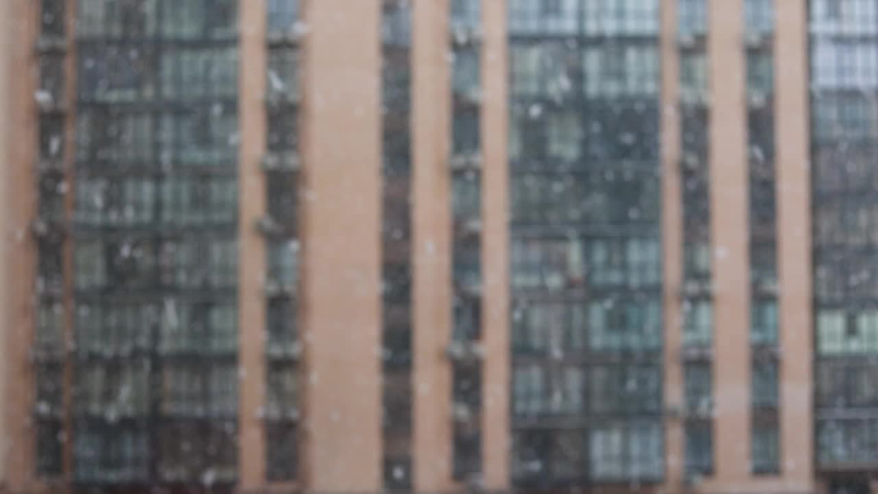 城市里下雪了。雪花飘落，背景是散乱的公寓楼和住宅区视频下载