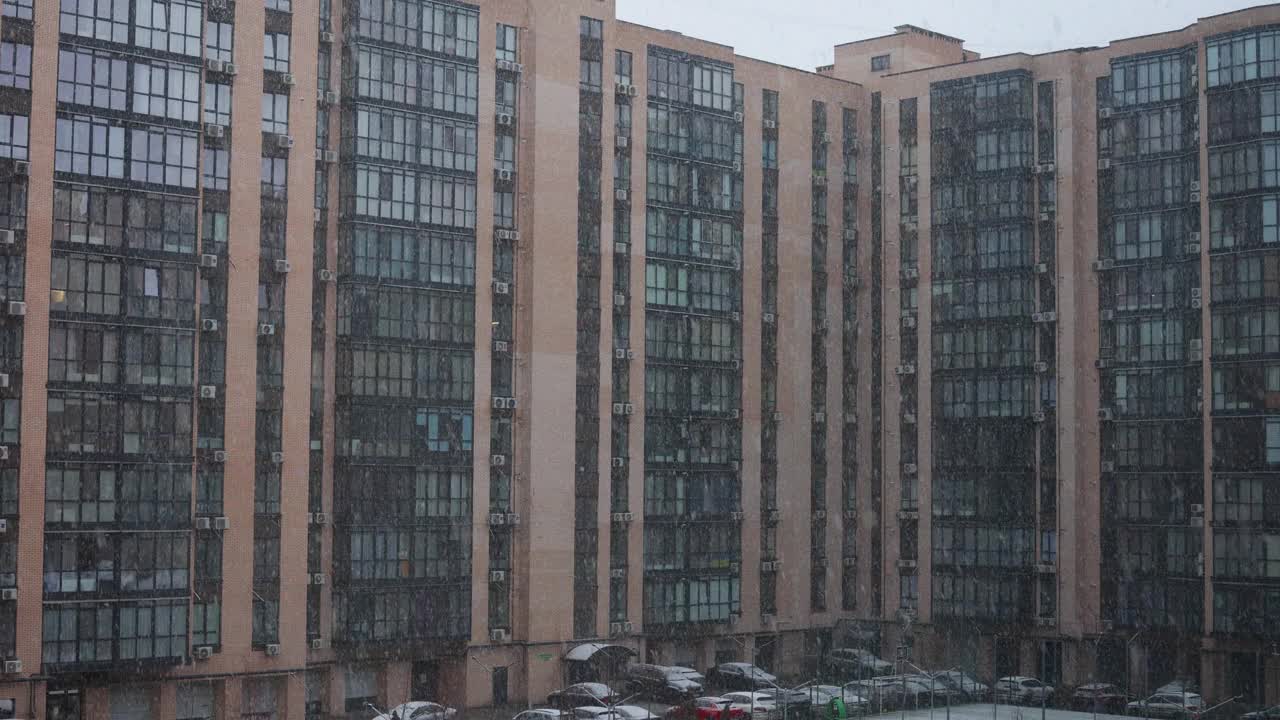 城市里下雪了。雪花飘落，背景是散乱的公寓楼和住宅区视频下载