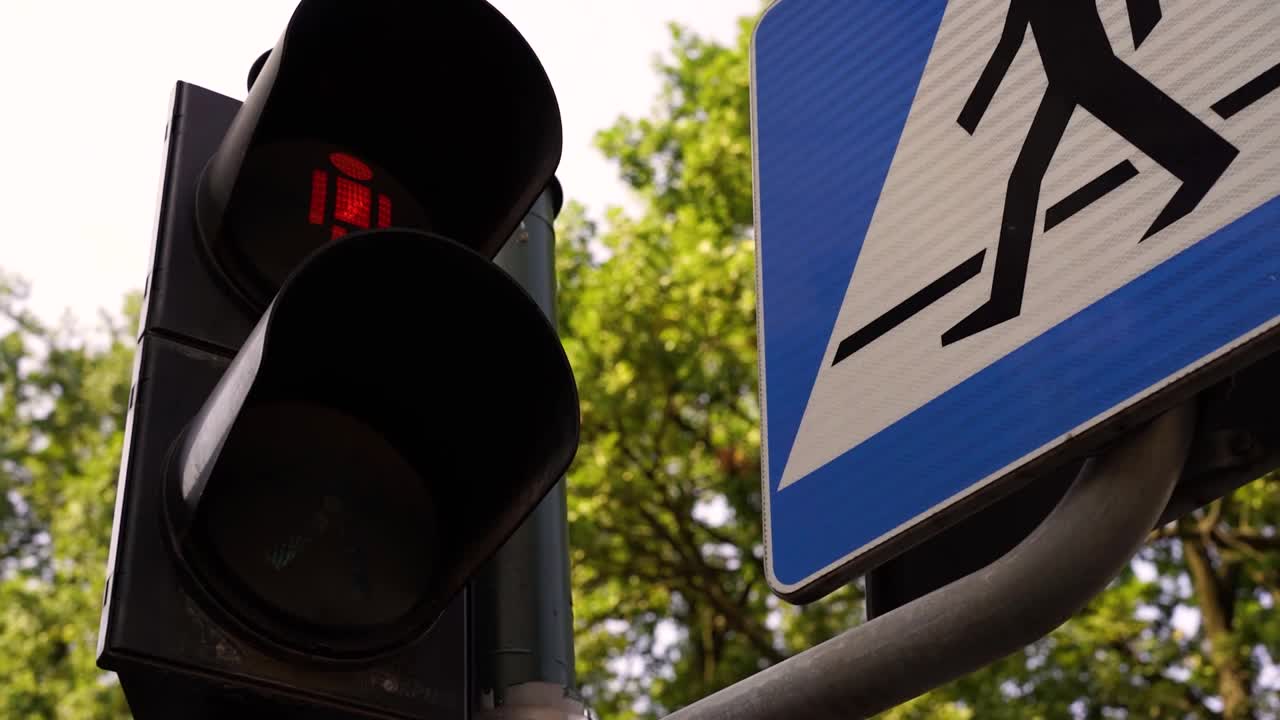 大型城市十字路口红绿灯特写，调节行人在街道上的移动，使道路上的人安全移动。道路设备交通管制。交通灯变亮。视频素材