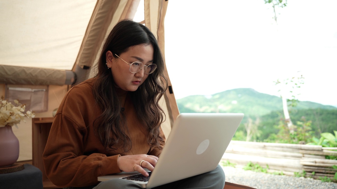 亚洲女性数字游牧民自由职业者在旅行露营时在laptopÂ上打字。视频素材