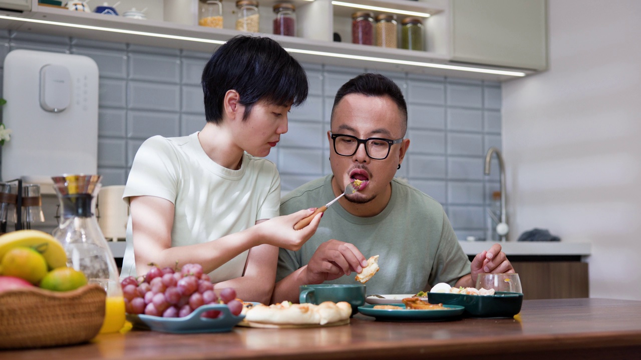 年轻的亚洲夫妇在家里的厨房里吃午饭视频素材