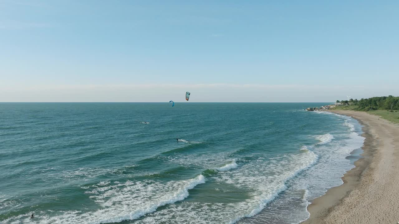 建立鸟瞰图，一群人从事风筝冲浪，阳光明媚的夏日，高浪，极限运动，波罗的海卡罗斯塔海滩(利耶帕亚)，宽无人机拍摄向前移动视频素材