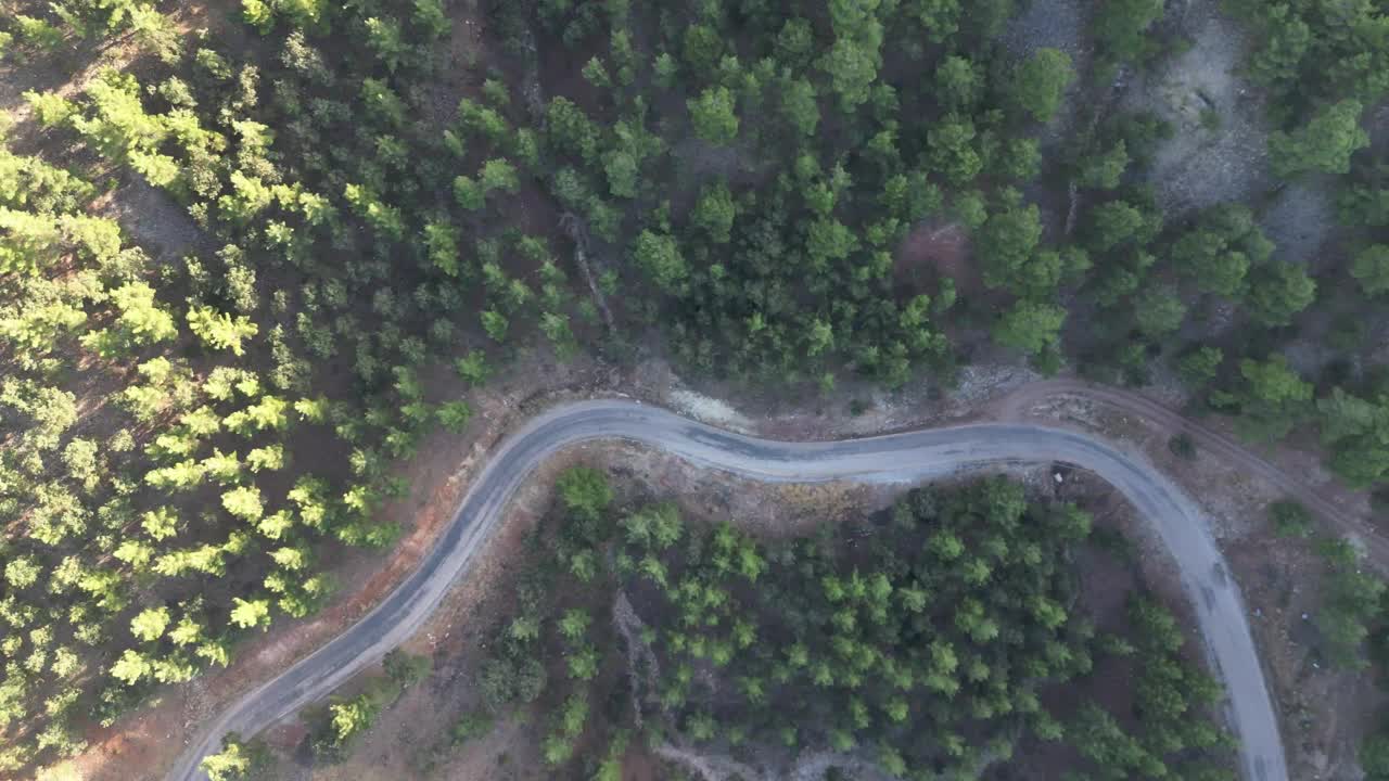 空中俯瞰蜿蜒的柏油路，山上有一辆移动的汽车。视频下载