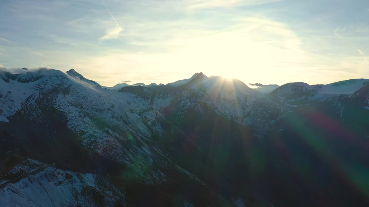黄昏鸟瞰白雪覆盖的阿尔卑斯峰顶与夕阳的光束，奥地利的霍赫陶恩国家公园视频下载