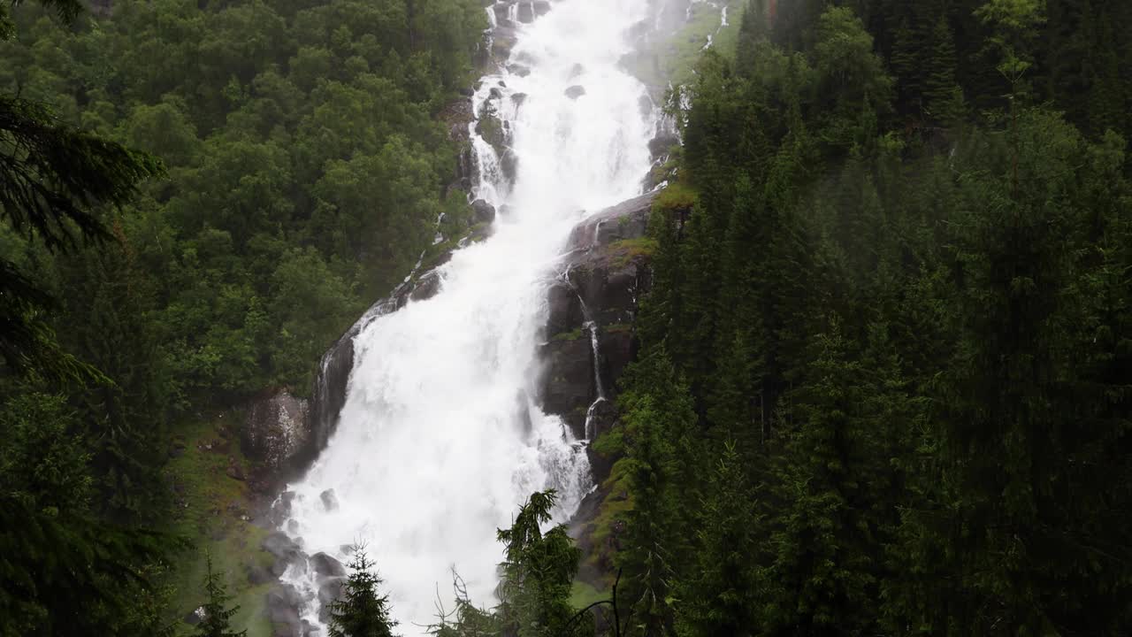 多云雨天的Tjornadalsfossen瀑布，周围环绕着挪威的绿色松林。水从陡峭的山面流下，在忧郁的日子里形成薄雾。视频下载