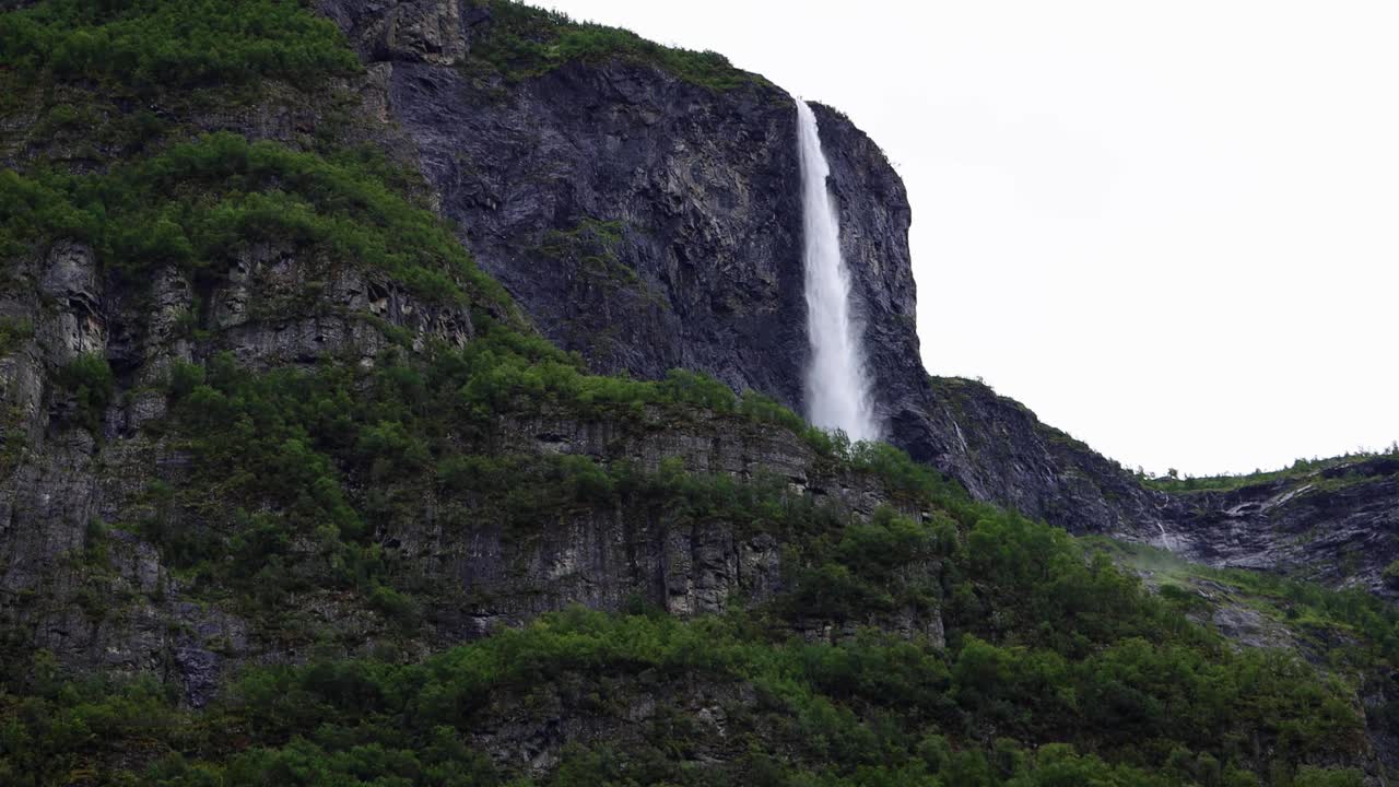 高大的瀑布从山顶落下，周围是陡峭的悬崖和松树林，挪威。视频素材