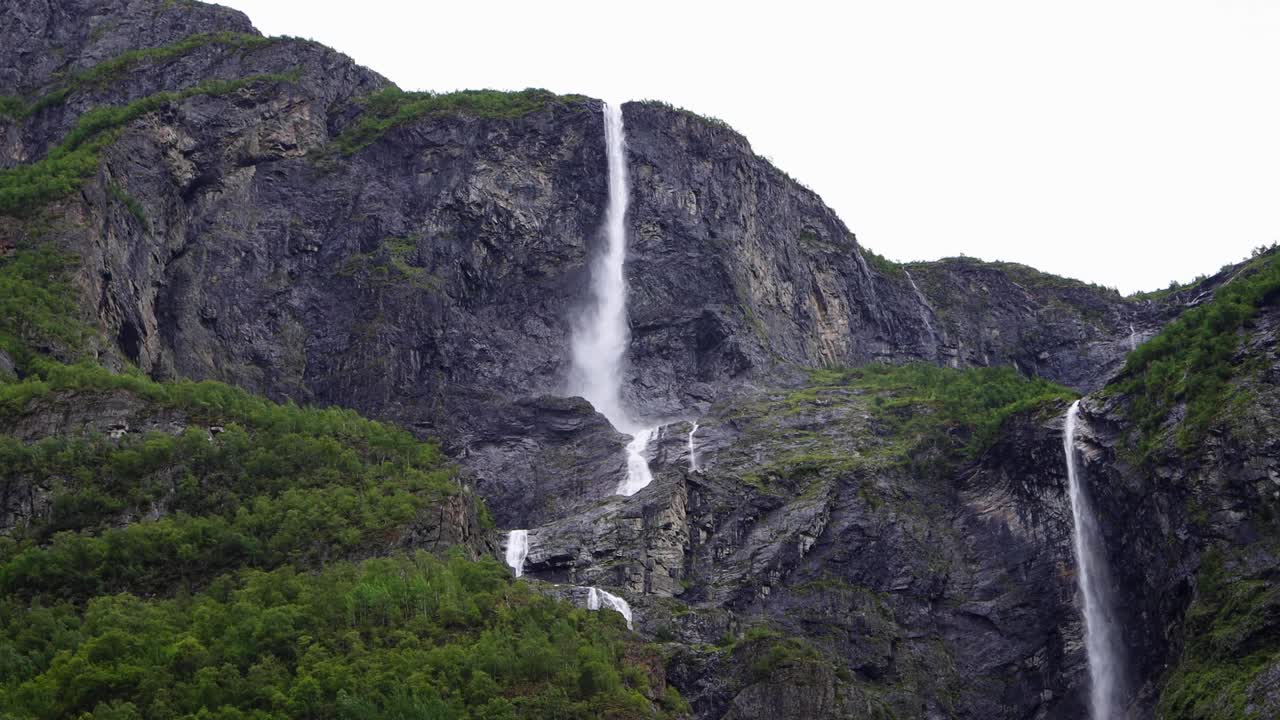 高大的瀑布从山顶落下，周围是陡峭的悬崖和松树林，挪威。视频素材