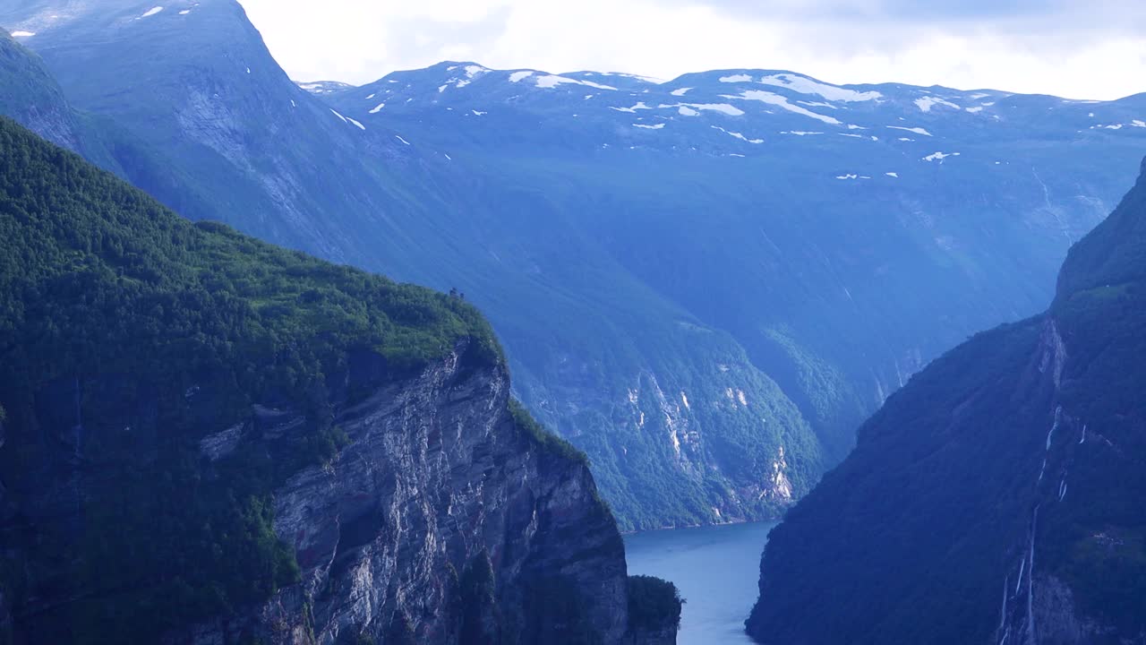 日落时挪威盖朗厄峡湾的景色。挪威峡湾高耸的高山，阳光透过云层照射进来。视频下载