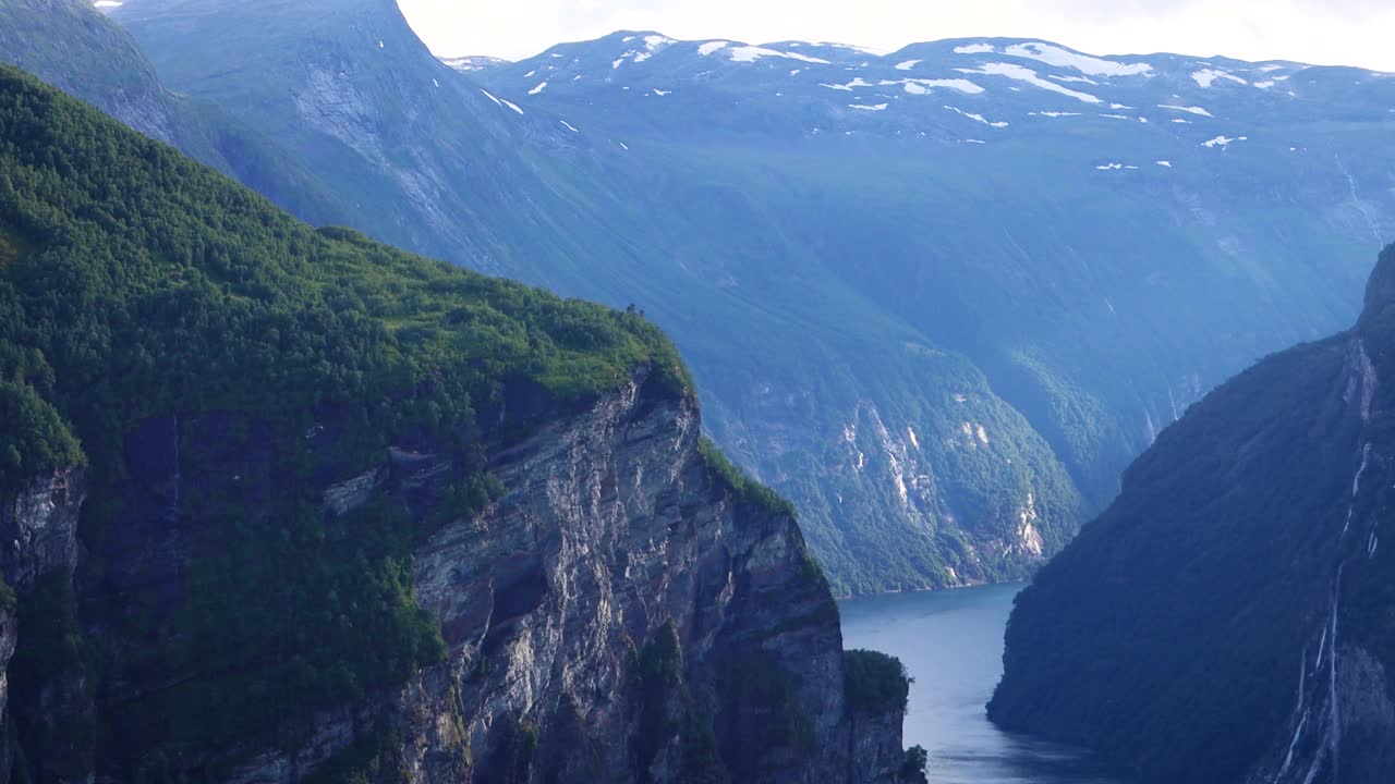 日落时挪威盖朗厄峡湾的景色。挪威峡湾高耸的高山，阳光透过云层照射进来。视频下载