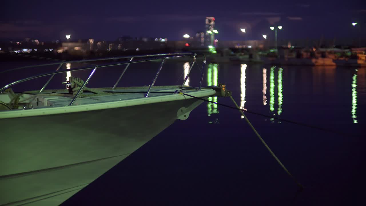 夜晚，傍晚，几艘船漂浮在港口的海面上，闪闪发光的灯光和水面上的倒影。视频素材