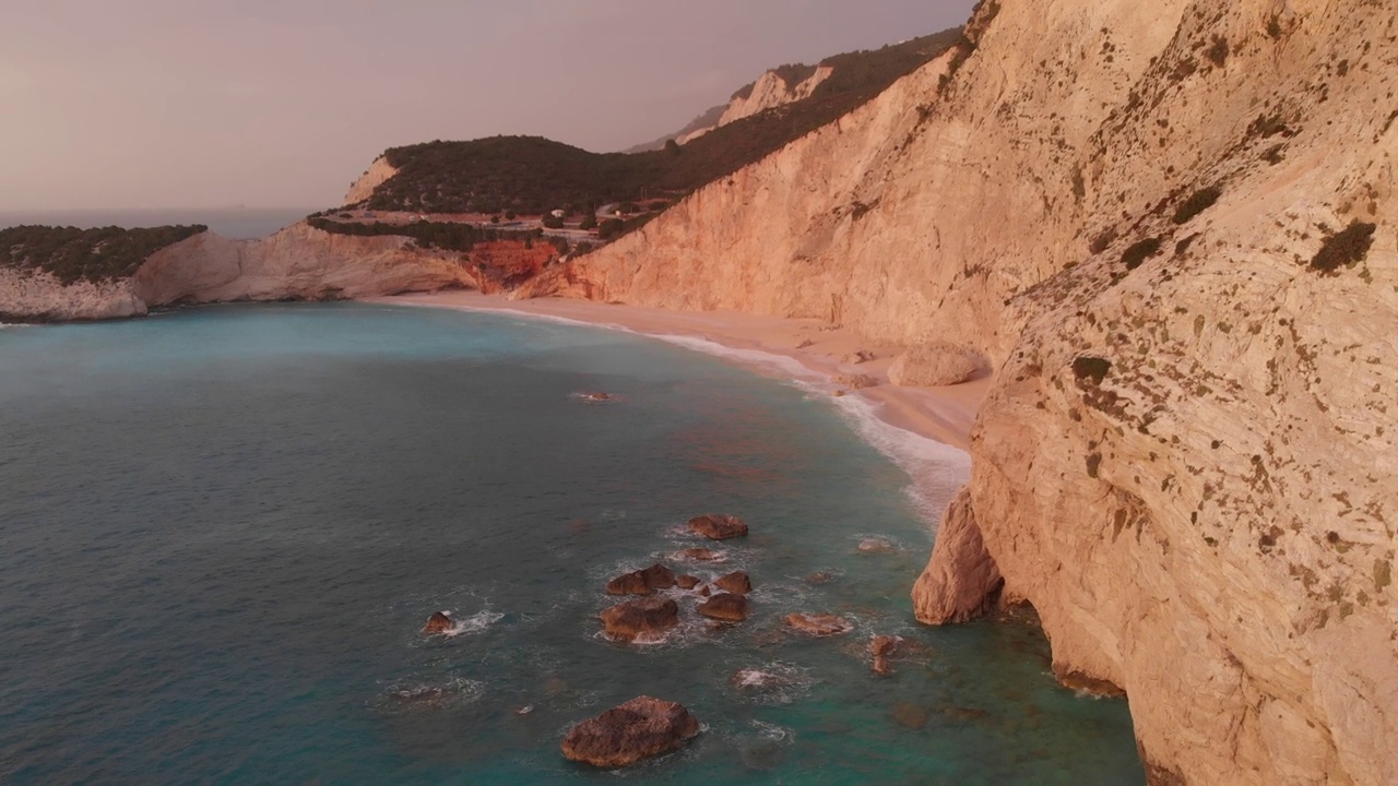 鸟瞰图:美丽的海滩和水湾在希腊壮观的海岸线。日落华丽的天空在蓝色的水独特的岩石悬崖。希腊夏季首选旅游目的地莱夫卡达岛视频下载