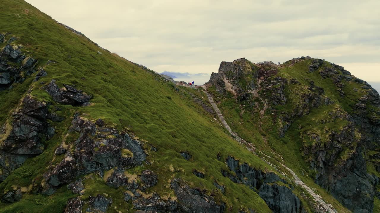 年轻的旅行者家庭在峡湾的顶端享受着渔村的壮丽景色。从上面看。视频素材