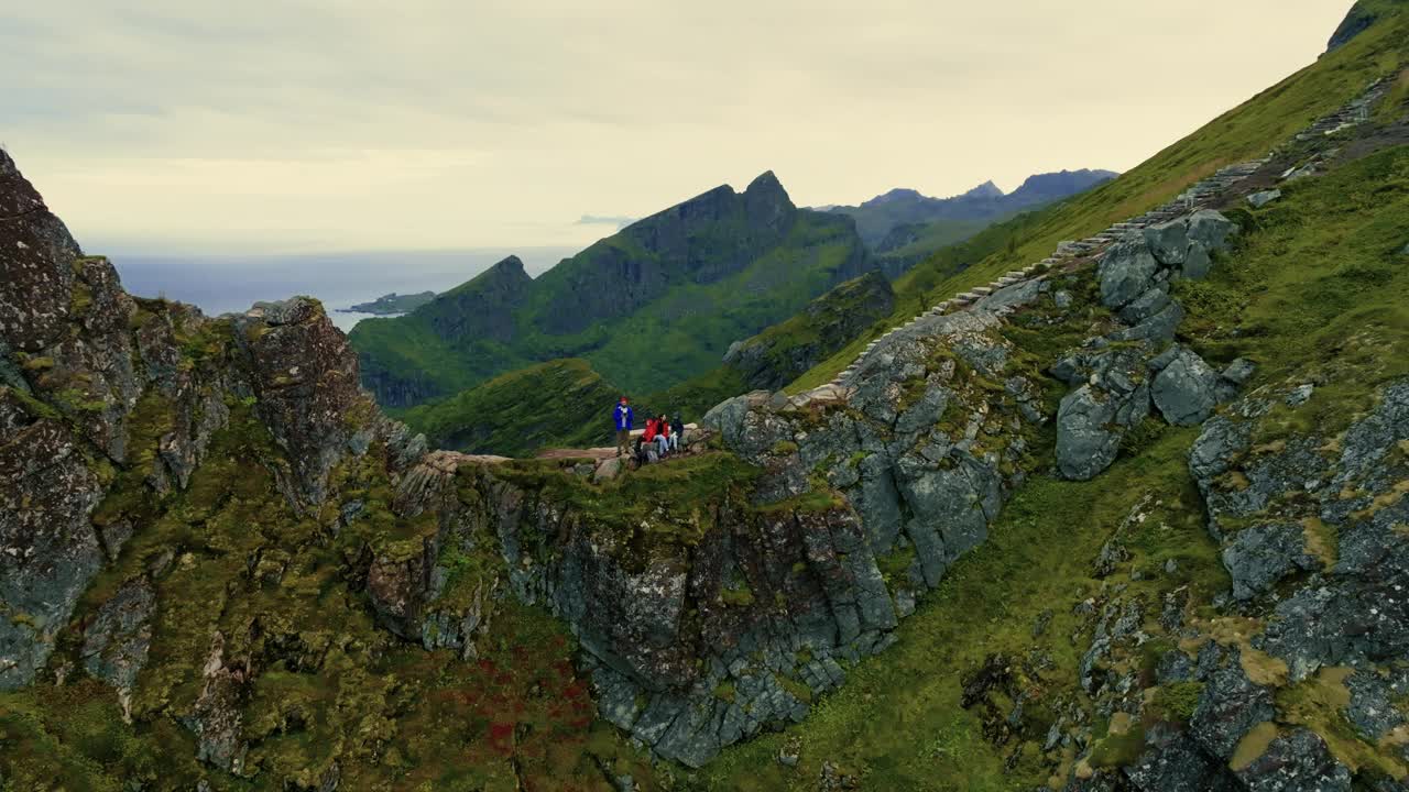 年轻的旅行者一家四口在岩石峡湾的山顶上，一起观察令人惊叹的北欧景色视频素材