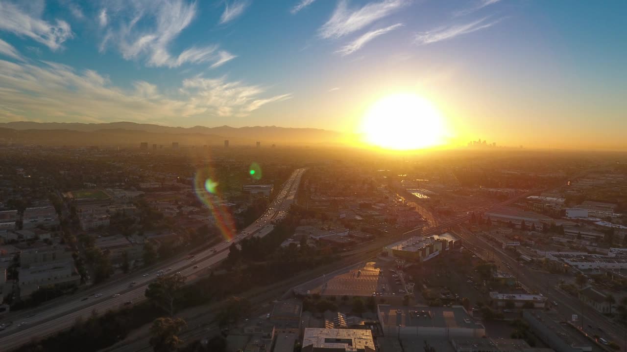 空中延时拍摄的车辆在高速公路上移动在城市的天空，无人机在日落期间飞越城市景观-卡尔弗城，加利福尼亚州视频素材